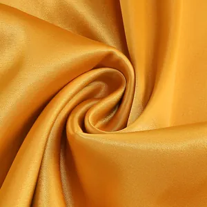 Primer plano de la textura de la tela de satén dorado sedoso con un brillo elegante