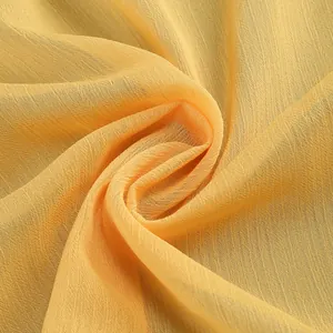 Vista detallada de la ligera tela de gasa plisada amarilla para un elegante vestido de noche