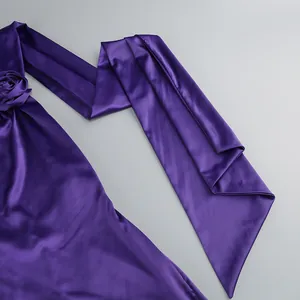 Primer plano de la elegante tela de satén púrpura y los detalles florales de este vestido halter.