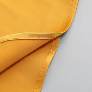 Primer plano del detalle de un vestido de satén amarillo con costuras suaves y tela