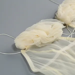 Detalle de vestido de gasa beige con decoración floral de volantes 3D hecha a mano elegante