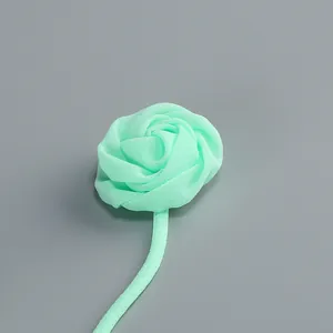 Vista detallada de una rosa de tela verde menta hecha a mano en un tirante de vestido