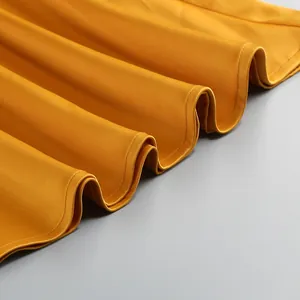 Detalle de primer plano de tela de satén amarillo liso con elegante dobladillo plisado