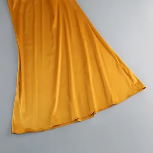Primer plano de un vestido de satén amarillo resaltando la tela suave y el dobladillo.