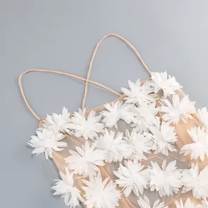 Detalle de vestido beige de malla con aplicaciones florales 3D blancas y finos tirantes
