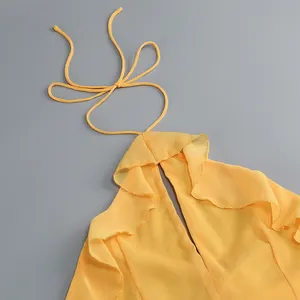 Detalle de un elegante vestido amarillo con cuello halter y delicados volantes de moda