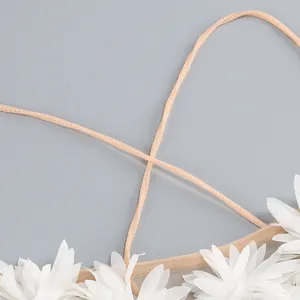 Detalle de tirantes cruzados albaricoque y flecos florales blancos en vestido de playa