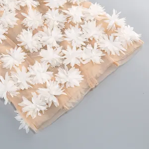 Vista detallada de aplicaciones florales 3D blancas en un vestido de tul para la playa.