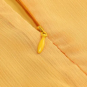 Detalle macro de la cremallera invisible en un vestido de noche de gasa naranja rugosa