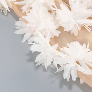 Primer plano detallado de elegantes flores de tela 3D blancas en un vestido de malla beige
