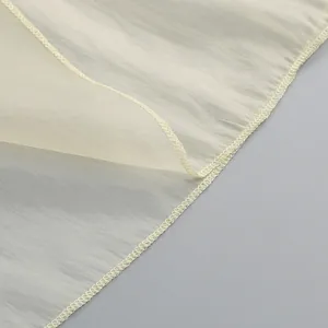 Primer plano de la textura de la tela crema transparente y detalle de dobladillo remallado