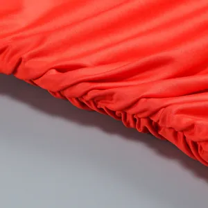 Vista macro del detalle de tela plisada y fruncida en rojo brillante para vestido ceñido