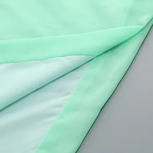 Vista macro que muestra la delicada textura de la gasa verde menta y el dobladillo
