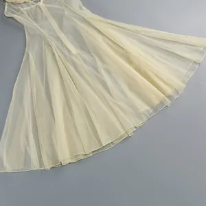Detalle del dobladillo de un vestido de organza amarillo claro con pliegues elegantes.
