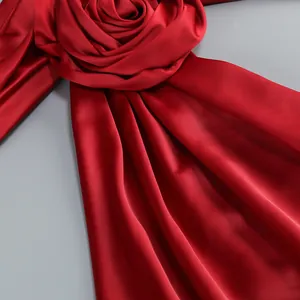 Detalle de una elegante rosa de tela de satén rojo intenso en un vestido de noche sedoso