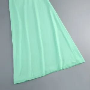 Primer plano del dobladillo de un vestido halter verde menta con textura de tela suave.