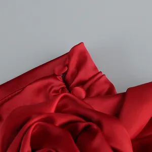 Detalle de vestido de noche de satén rojo de lujo con botones y textura plisada