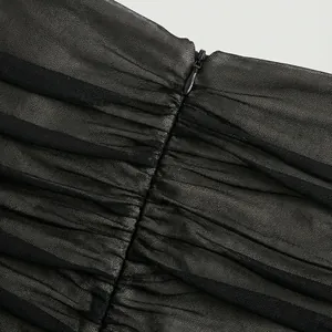 Detalle de vestido de malla negra fruncido con cremallera invisible de alta calidad.