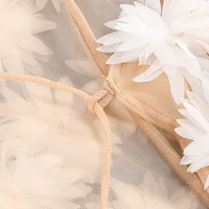Detalle de aplicaciones de flores 3D blancas en vestido de tul color melocotón.