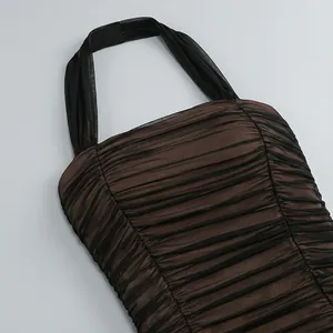 Vista de detalle de un vestido halter de malla fruncida marrón y negro con capas de pliegues.