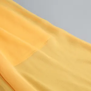 Primer plano de la elegante tela de gasa plisada amarilla de un vestido de noche de lujo