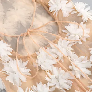 Detalle de vestido de malla con apliques de flores 3D y finos tirantes de cordón.