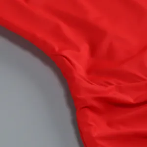 Primo piano del tessuto di un abito rosso elegante con cuciture fini e trama drappeggiata.