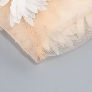 Detalle macro de vestido de verano con tela de tul beige y aplicaciones de pétalos blancos