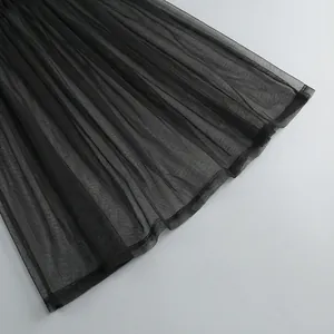 Primer plano de la fina tela de malla negra con elegantes detalles plisados en un vestido chic