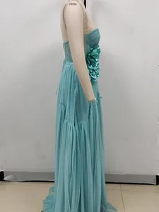 Side view of turquoise tulle maxi dress featuring large 3D floral embellishment on the bodice.
