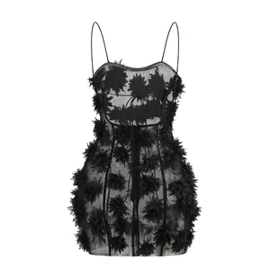 Primer plano de un vestido negro de tirantes con aplicaciones florales 3D y textura de malla