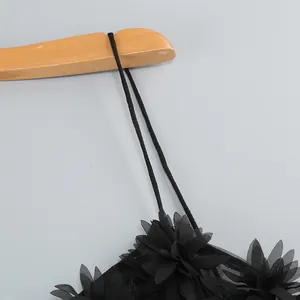 Detalle de vestido de malla negra con aplicaciones florales en 3D y tirantes finos