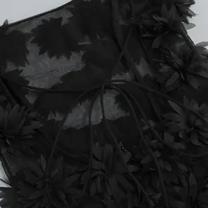 Detalle de vestido de malla negra con apliques florales 3D y diseño de cordones