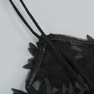Detalle de un vestido de playa negro de malla con tirantes finos y flecos