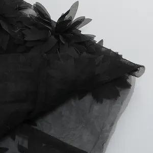 Primer plano detallado de un vestido de malla negra con elegantes apliques de flores 3D