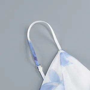 Close-up of adjustable spaghetti strap on a white and blue floral print satin dress.