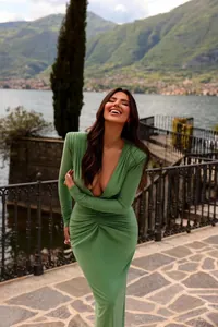 Vista completa de una modelo con un vestido largo fruncido verde salvia al aire libre