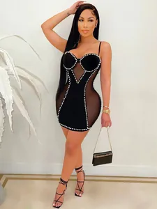 Vista detallada de un vestido de vendaje negro con malla y adornos de perlas