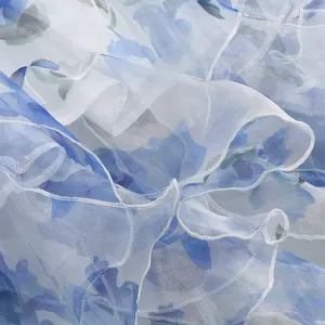 Close-up detail of blue floral pattern on white ruffled chiffon fabric of a French dress
