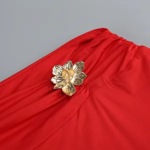 Primer plano de una flor metálica dorada sobre la tela fruncida de un elegante vestido rojo