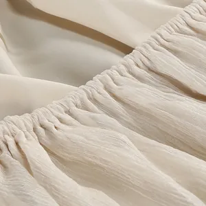 Primo piano che mostra la delicata trama plissettata del tessuto a rete crema del vestito