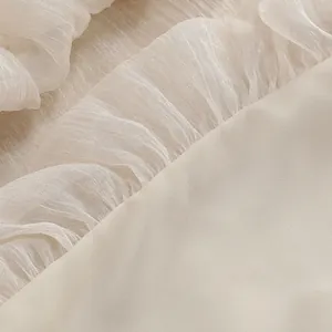Dettaglio macro di un elegante tessuto a rete plissettato crema con morbidi volant