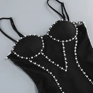 Primer plano del vestido de vendaje de malla negra con adornos de perlas cosidos a mano en el busto