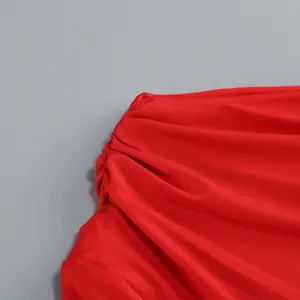 Primer plano de tela roja acanalada con detalle fruncido en el hombro del vestido largo.