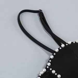 Primer plano de un vestido negro con tirantes y adornos de perlas cosidos a mano