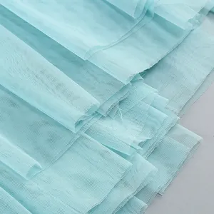 High-quality close-up detail showing light blue layered mesh fabric of a summer dress