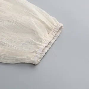 Primo piano dettagliato del polsino elasticizzato di un abito estivo in rete crema