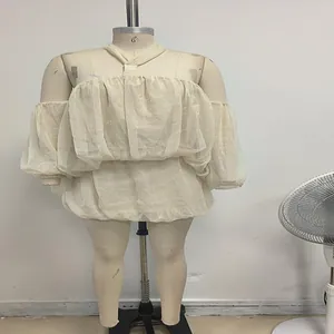 Dettaglio di abito in rete beige con spalle scoperte e maniche a sbuffo