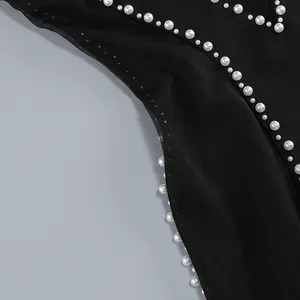 Primer plano del vestido de malla negra con perlas blancas cosidas a mano y pedrería.