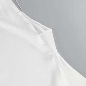 Close-up of white mesh fabric detail and fine stitching on an elegant evening dress.